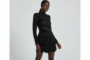 Model wearing black mini dress with sheer floral burnout velvet details, long sleeves and elegant mock neckline