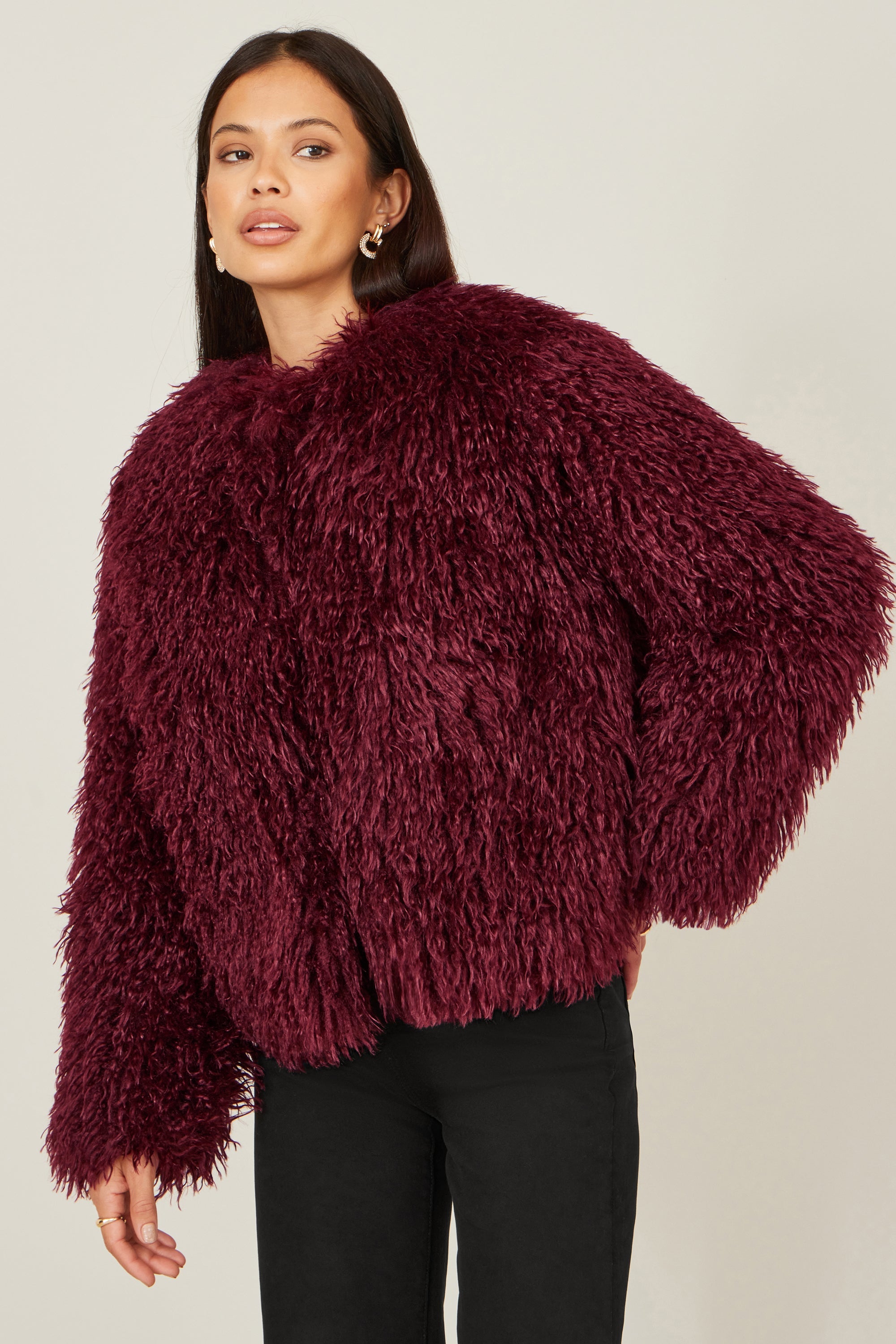 Woman wearing burgundy fluffy faux fur coat - party season statement outerwear